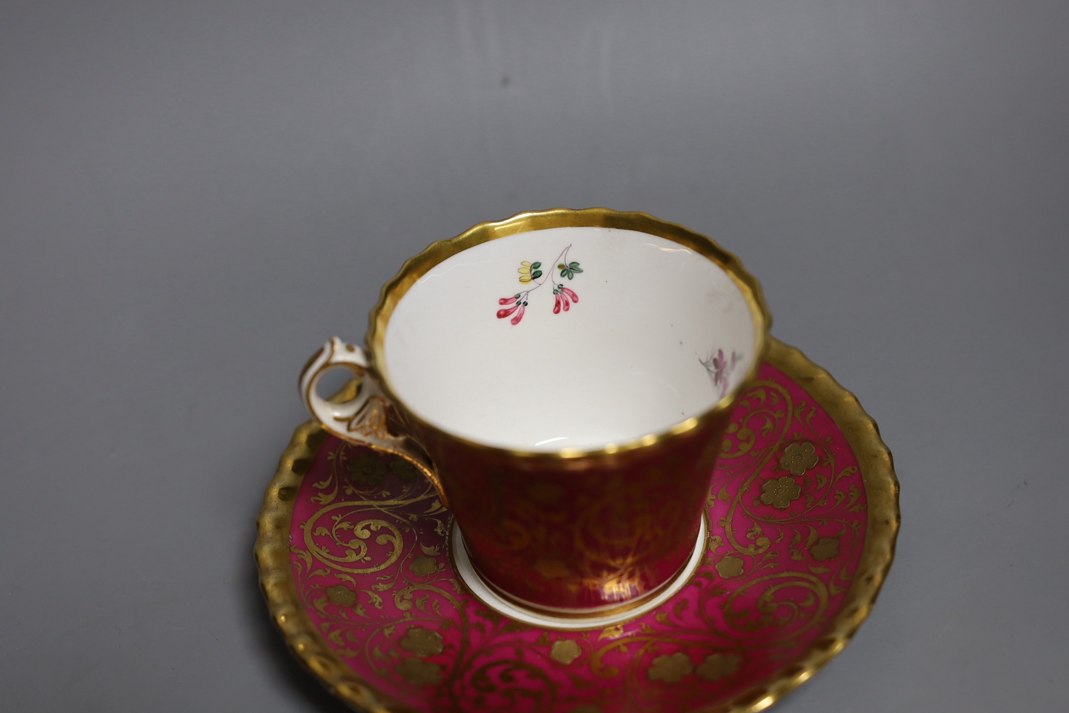 A Chamberlains Worcester superb coffee cup and saucer with crinson ground and elaborate gilding the saucer painted with flowers, the cup painted with flowers in and out, script mark in red to cup